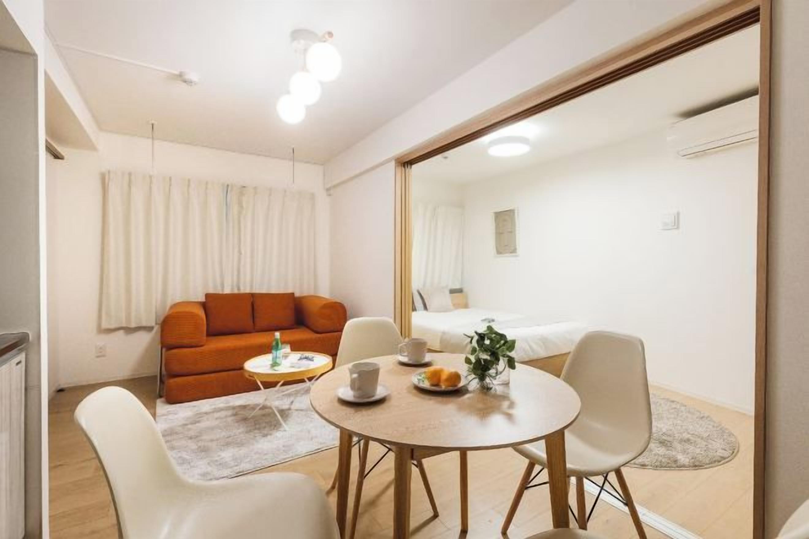 A modern living room with a sofa, a dining table with chairs, and a large mirror.