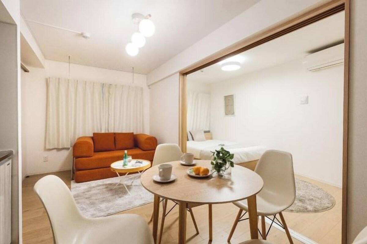 Un salon moderne avec un canapé, une table à manger et des chaises, ainsi qu’un grand miroir.