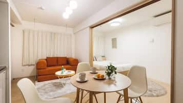A modern living room with a sofa, a dining table with chairs, and a large mirror.
