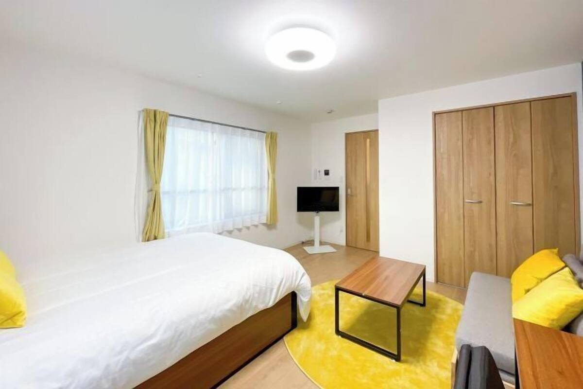 Una camera d'albergo con un letto, una televisione, un armadio in legno e un divano.