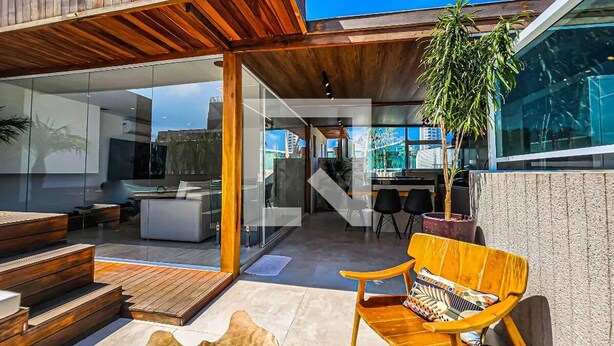 A modern outdoor living area with a wooden bench, a potted plant, and a glass door leading to the interior. - Apartment in Guarujá, 7 minutes from the beach (Guarujá)