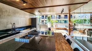 A modern kitchen with a central island, a built-in stove, and a large window overlooking a courtyard. - Apartment in Guarujá, 7 minutes from the beach (Guarujá)