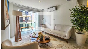 A modern living room with a sofa, coffee table, and potted plant. - Apartment in Guarujá, 7 minutes from the beach (Guarujá)