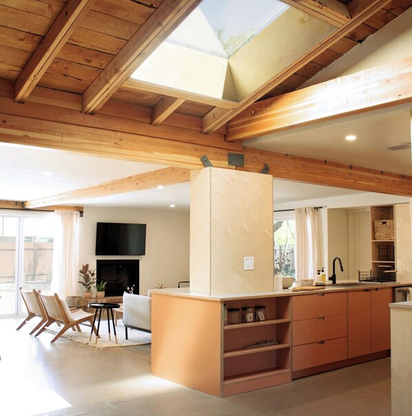 Eine moderne Küche mit Holzbalken, einer integrierten Kochinsel und einem Fernseher über dem Kamin.