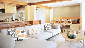 Una sala moderna con un sofá, un comedor con una mesa y sillas, y una cocina al fondo.