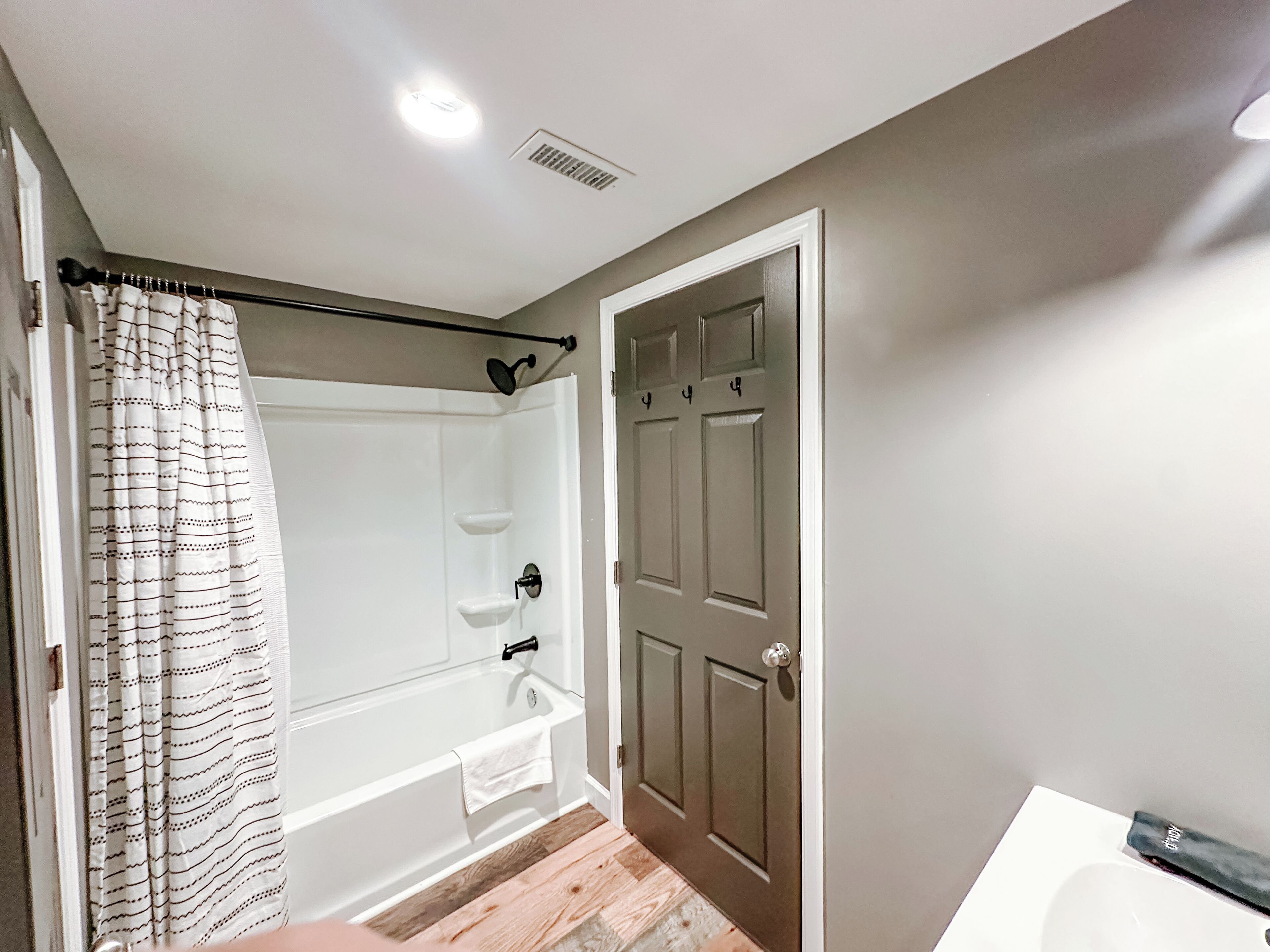 A bathroom with a bathtub, shower, and a door with four locks.