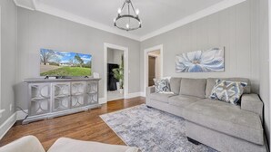 A living room with a grey sofa, a white cabinet, and a chandelier. - Cottage in the Pines (Rocky Mount)