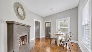 A dining area with a fireplace, a round table, and chairs. - Cottage in the Pines (Rocky Mount)