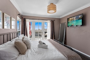Quarto de hotel com uma cama, televisão e vista para o exterior.