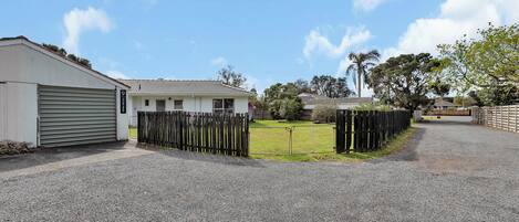 A residential property with a garage, a fenced yard, and a gravel driveway.