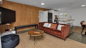 Un salon moderne avec un canapé marron, une table basse et un téléviseur fixé à un mur en bois.