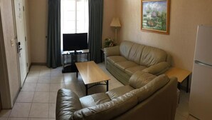 Un soggiorno compatto con divano, un tavolino, televisore e lampada.