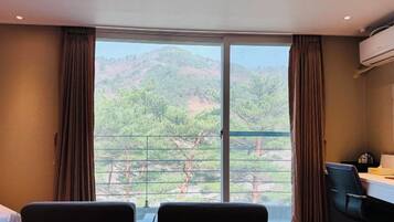 A room with a large window, two chairs, a desk, and an air conditioning unit.