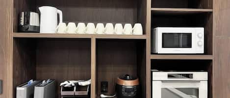 A kitchen with a microwave, toaster, kettle, and a coffee maker on the shelves.