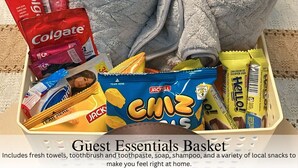 A guest essentials basket with towels, toiletries, and snacks.