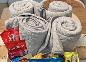 Una cesta con artículos esenciales para huéspedes, incluyendo toallas, artículos de aseo y refrigerios.
