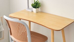 A wooden desk with a white chair, a desk lamp, and a small potted plant.