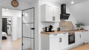 Una cocina moderna con armarios blancos, una campana extractora negra y una encimera de madera.
