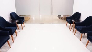 A conference room with a white floor, dark blue chairs, and a small table at the front. - Cordia Hotel Yogyakarta - Airport Hotel (Temon)