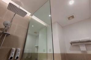 Un baño moderno con cabina de ducha de vidrio, un perchero para toallas y un cabezal de ducha de mano.