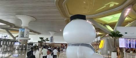 A spacious airport terminal with a large spherical sculpture and a modern ceiling design.