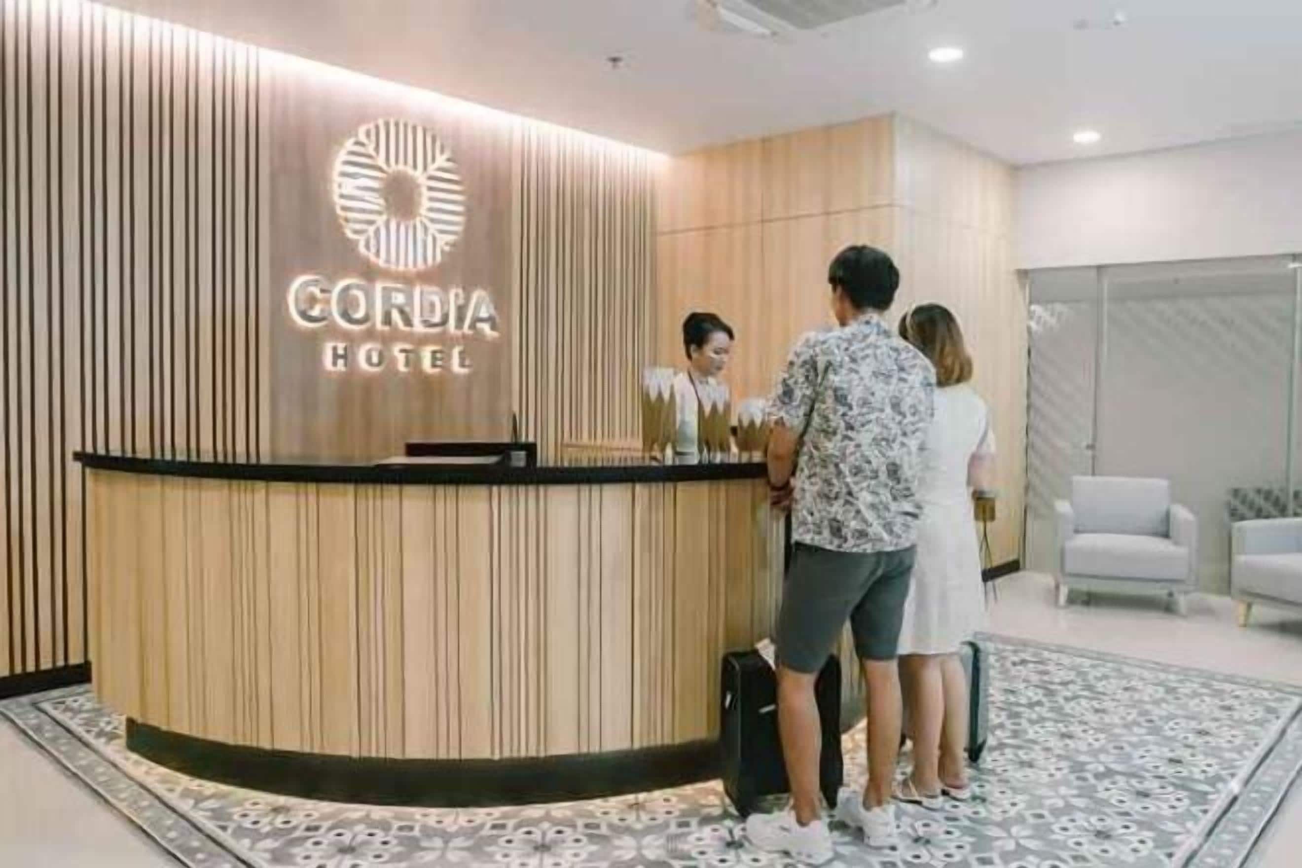 A hotel reception desk with a modern design, a logo above the desk, and a reception area with seating.