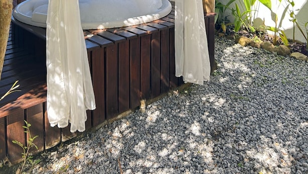 Un bain à remous entouré d’arbres et adossé à un mur blanc.