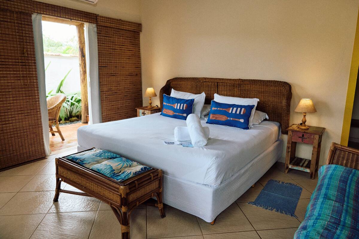Een hotelkamer met een groot bed, een klein tafeltje, een stoel en uitzicht op het omliggende landschap.