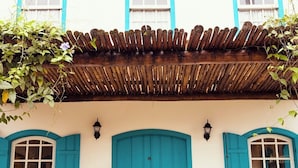 Un bâtiment à la façade blanche, aux volets bleus et au toit en bois.