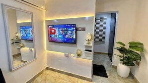 Um interior moderno com uma TV de tela plana fixada na parede, um espelho grande e um vaso de planta.