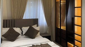 Quarto moderno com cama grande, cortinas e guarda-roupa embutido com painéis iluminados.