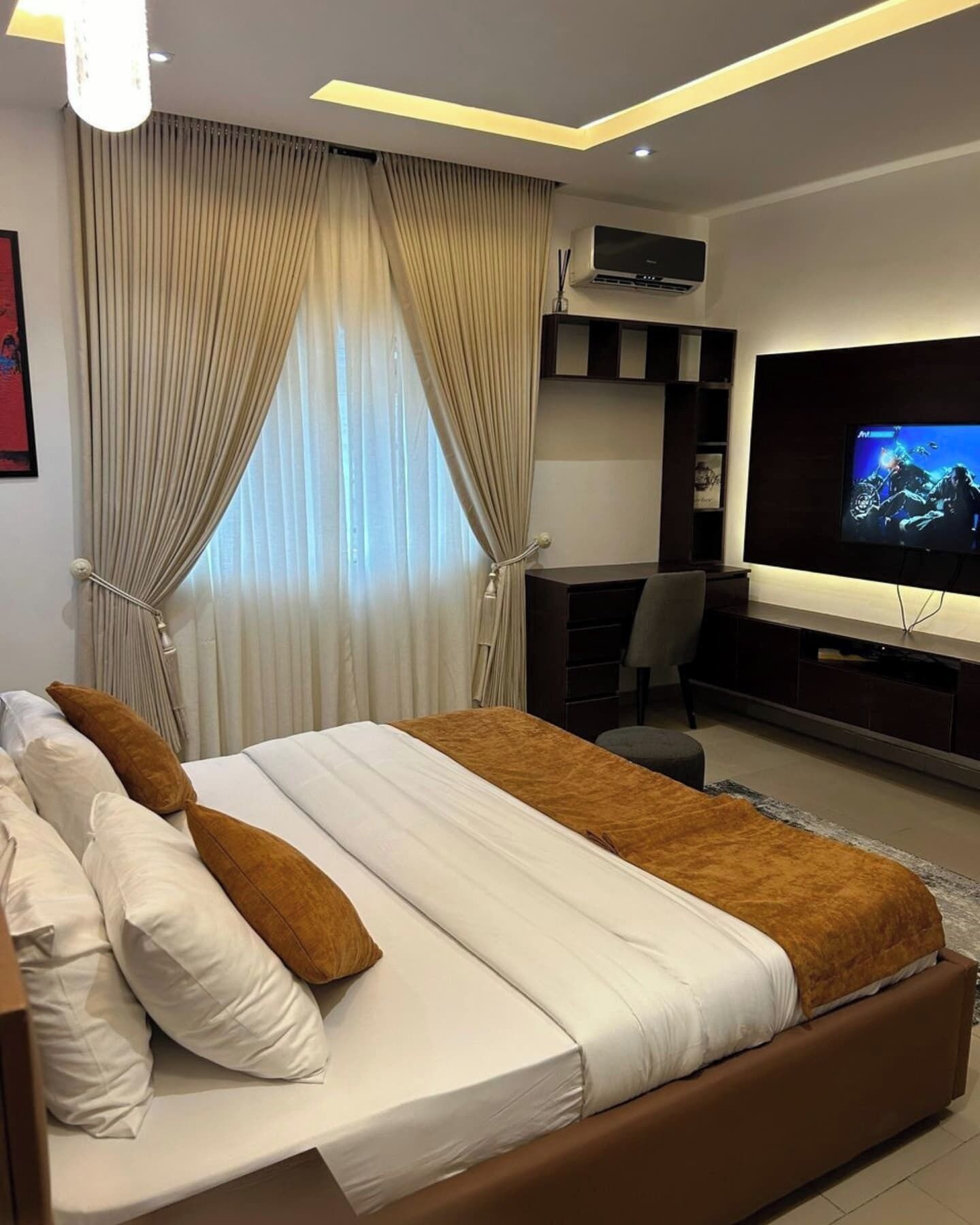 A modern hotel room with a large bed, a desk, and a television.