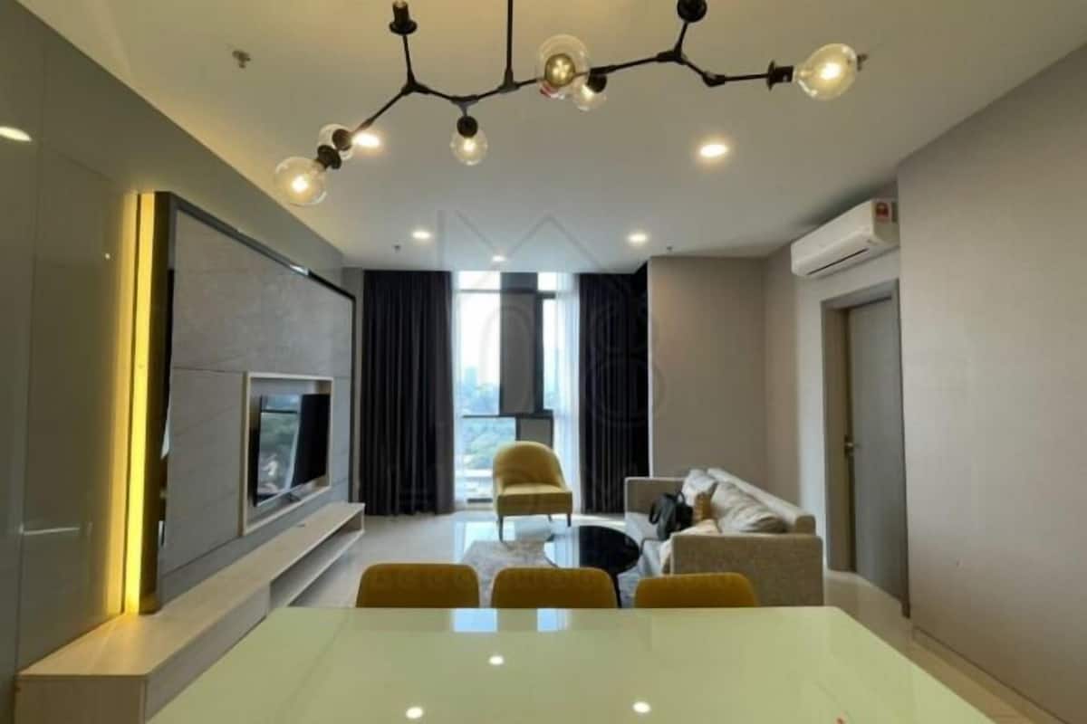 A modern living room with a flat-screen TV, a dining table with chairs, a sofa, and a yellow armchair.