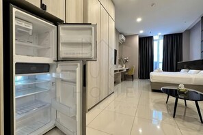 Ein Hotelzimmer mit Bett, Essbereich, Küche mit offener Kühlschrank und Bad.
