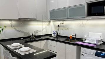 A modern kitchen with a marble backsplash, black countertops, and a built-in washing machine.