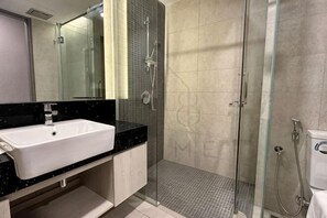 Ein modernes Badezimmer mit einem weißen Waschbecken, einer Duschkabine aus Glas und einem großen Spiegel.