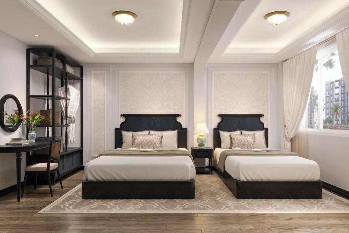 A hotel room with two beds, a desk, a chair, and a large window.