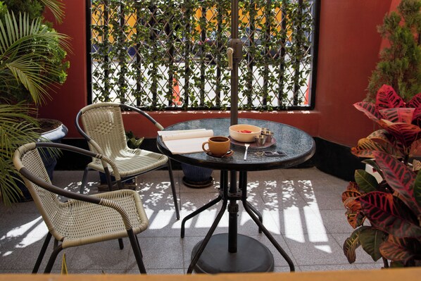 A patio area with wicker chairs, a round table, and a view through a lattice window. - Kontiki Miraflores (Lima)