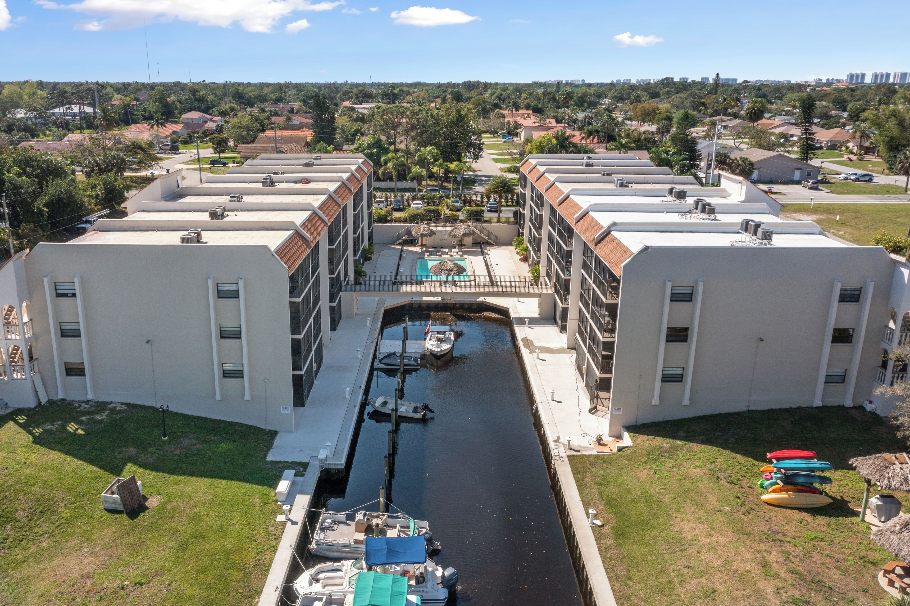 A multi-story building with a central courtyard featuring a swimming pool, boats, and a small dock.