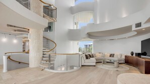 Amplia sala de estar con una escalera curva, un conjunto de sofás y una mesa de centro.