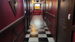 A hallway with a checkered floor, red walls, and doors on both sides. - Sisilli Motel (Uijeongbu)
