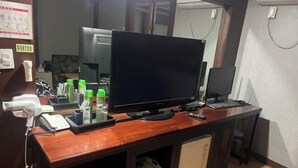 A wooden desk with a flat-screen TV, a computer, and various office supplies. - Sisilli Motel (Uijeongbu)