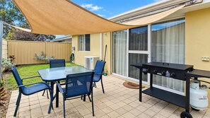 A patio with a table and chairs, a barbecue grill, and a gas cylinder. - Cape View TwentyTwo – a modern 2-bedroom, 2-bathroom villa (Broadwater)