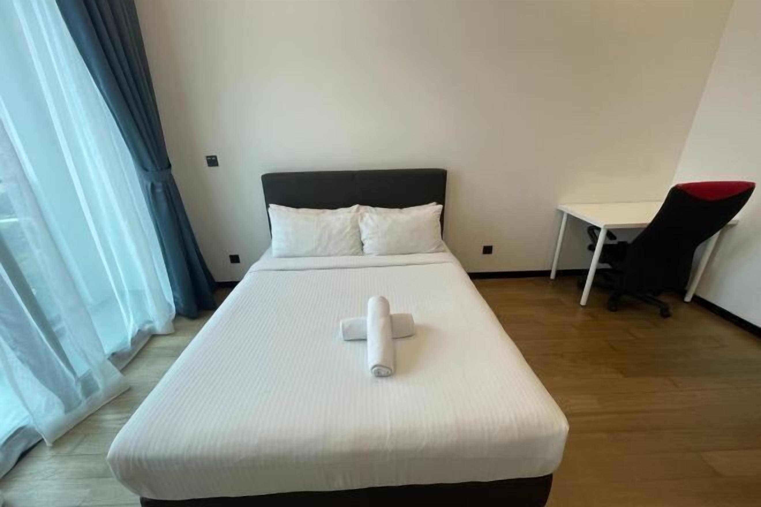 A neatly made bed with white linens, a black headboard, and a white pillow.