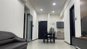 Een moderne woonkamer met een bank, een eettafel met stoelen, een keuken met kasten en een zwarte deur.