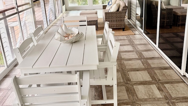 Une vaste terrasse dotée d’une table et de chaises, d’un canapé et d’un ventilateur de plafond.