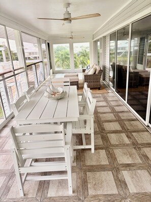 A spacious patio with a dining table and chairs, a sofa, and a ceiling fan. - 3BR Coastal retreat in peaceful Bokeelia with pool, bikes, ping pong and fishing (Bokeelia)