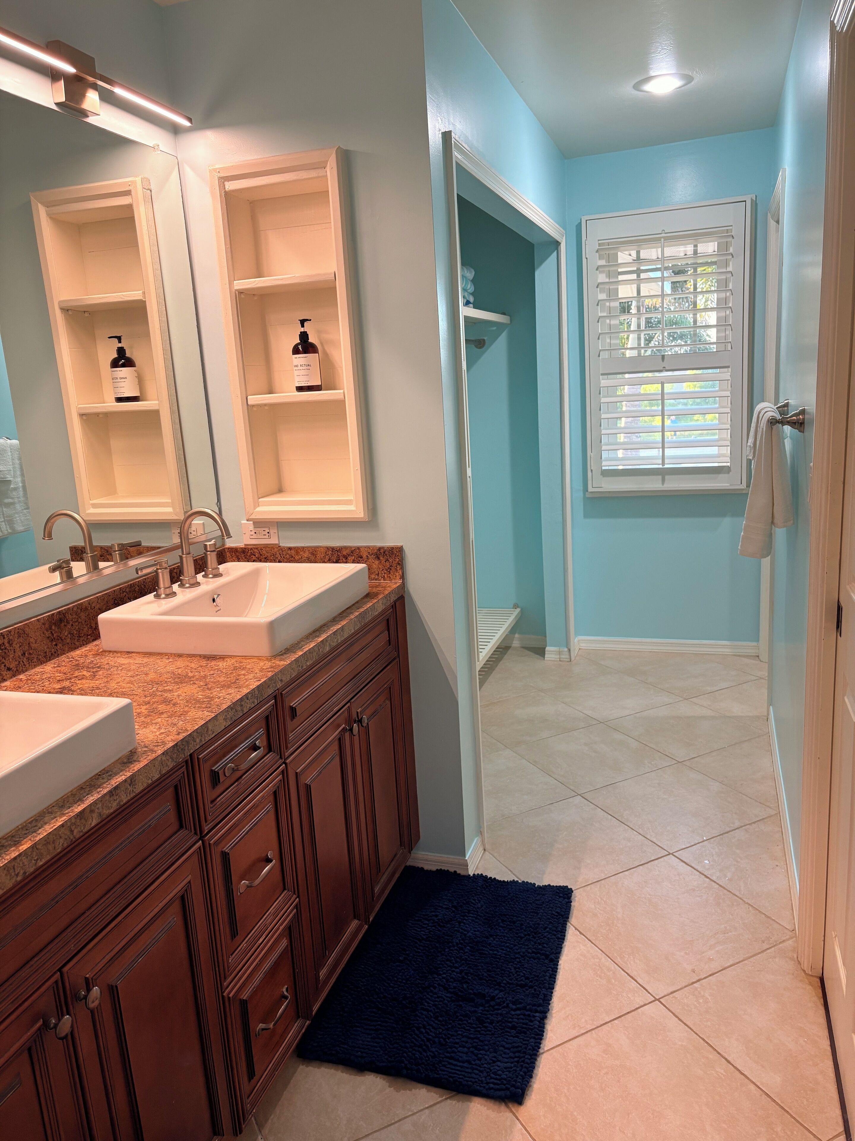 A bathroom with two sinks, a mirror, and a shower area.