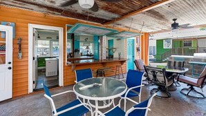 A rustic outdoor seating area with a glass table and blue chairs, a bar with a green counter, and a view of the surrounding area. - EAGLES NEST #1 AT SUN PERCH VILLAS. BEAUTIFUL VIEWS OF FALSE RIVER! (Ventress)