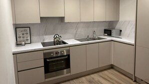 Une cuisine moderne équipée d’un four encastré, d’un four à micro-ondes, d’une bouilloire et d’un évier.
